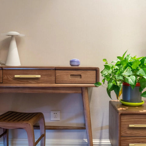 Desk with Four Pack 3 Inch Solid Brass Cabinet Pulls in Brushed Gold Finish on wood drawers in a modern room with plant decor.