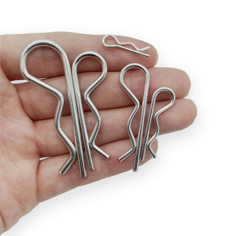 Hand holding 38 Piece Hitch Pin Clip Set With Five Sizes For Trailer And Tractor Applications Including Hair Pins R Clips Retaining Pins Spring Clips And Dolly Pin Replacement Kit By Yoliko.