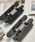 Heavy Duty Concealed Kitchen Cabinet Hinges That Roll Out Smooth Hydraulic Soft Close And Offer A Full 180 Degree Swing For Dead Easy Install and Clean Hidden Storage Hardware In Matte Black, two units laid on a surface.