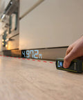 Pro 20 Meter Laser Distance Meter With Clear Digital Screen And Continuous Measurement Mode measuring 4.97m on wooden floor.