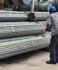Worker handling stacked metal pipes in an industrial setting