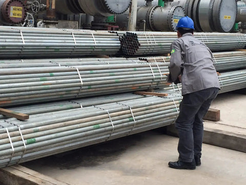 Worker handling stacked metal pipes in an industrial setting