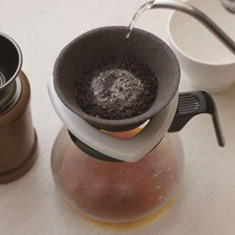 Japanese Ceramic Coffee Filter With Reusable Blue Dripper Stand And Eco Friendly Micropore Design For A Smooth Next Level Pour Over Brew That Truly Hits Different in use with water pouring over coffee grounds.