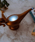 Aladdin Genie Lamp LED Mood Light 10 Inch Blue And White Mood Lighting Figure Collectible Genie Lamp Decor Epic Glow Night Light For Fans And Collectors beside books and toy dinosaur on marble surface.