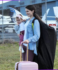 Mother carrying a Large Stroller Travel Bag For Airplane Use Waterproof Nylon Construction Fits Most Large Single Double And Jogging Strollers Black And Green 47 H X 24 W X 15 D With Premium Tear Resistant Cover And Adjustable Shoulder Straps next to airplanes.