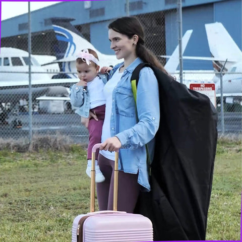 Mother carrying a Large Stroller Travel Bag For Airplane Use Waterproof Nylon Construction Fits Most Large Single Double And Jogging Strollers Black And Green 47 H X 24 W X 15 D With Premium Tear Resistant Cover And Adjustable Shoulder Straps next to airplanes.