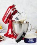 Red stand mixer with open whisk attachment next to 4 oz jar of NSF-certified food grade grease for stand mixer gears and moving parts.