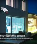 Realistic Fake Surveillance Camera 2 Pack With LED Light installed on outdoor wall of modern house, red LED visible at night.
