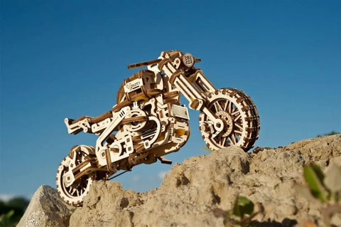 Scrambler UGR 10 Mechanical Model Kit With Working Rubber Band Motor Moving Pistons Belt Driven System 3D Puzzle Craft For Adults Totally Dope Hobby Build Classic Dual Sport Motorcycle Replica wooden model on rocky slope
