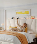 Queen Bed Frame With Smart Led Lights And Dual Usb Ports App Remote Music Sync And Custom Timer For A Lowkey Dreamy Bedroom Setup Solid Noise Free Platform In Cozy Beige with a woman relaxing against a velvet headboard.