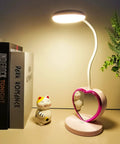 Cute Pink Desk Lamp With USB Charging Port, Pen Holder And Phone Stand, placed on a desk next to books and a small figurine.