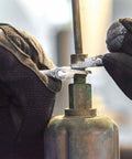 Hands using 4-inch adjustable wrench with slimmer 40% jaws, high polish chrome finish on gas line fitting.