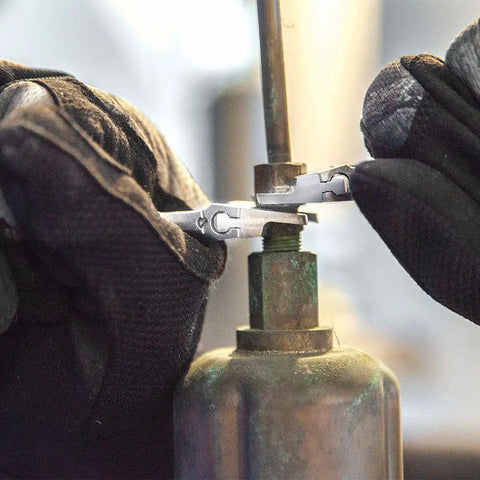 Hands using 4-inch adjustable wrench with slimmer 40% jaws, high polish chrome finish on gas line fitting.