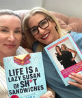 Two women holding the book 'LIFE IS A LAZY SUSAN OF STRAIGHT FIRE ADVICE AND KEEPING IT REAL WISDOM' in a cozy setting.