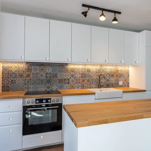 Modern kitchen with white cabinets, a wood countertop, and a decorative tiled backsplash featuring various patterns.