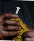 Close-up of hands holding a single metal screw from 6 Pcs Roller Skate Stopper Screws For Quad Skates Replacement Parts With Easy Installation.