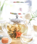 All In One Glass Teapot And Kettle With Heatproof Borosilicate Glass Removable Stainless Steel Infuser Microwave And Stovetop Friendly Tea Maker For Everyday Tea Lovers 40 Oz 1200 Ml on a table with blooming tea