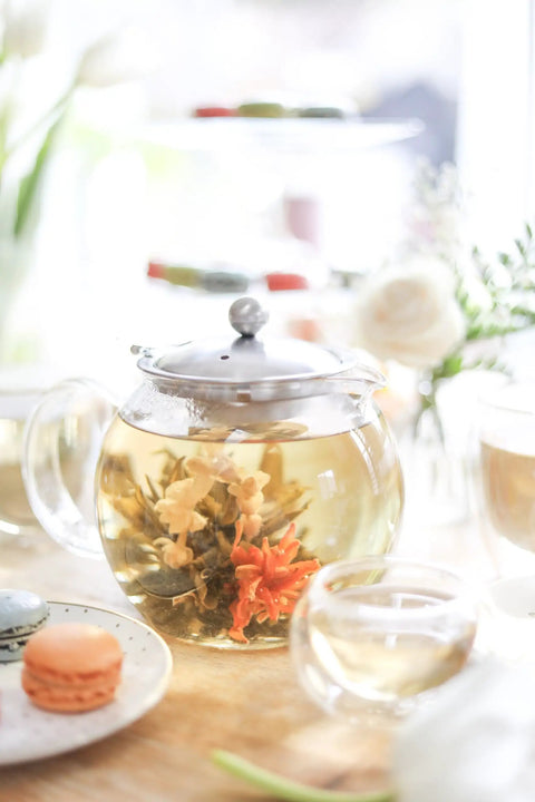 All In One Glass Teapot And Kettle With Heatproof Borosilicate Glass Removable Stainless Steel Infuser Microwave And Stovetop Friendly Tea Maker For Everyday Tea Lovers 40 Oz 1200 Ml on a table with blooming tea