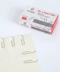 No Slip Paper Clips Set, 600 Count In Six Boxes Of 100 Each, One And Two Sevenths Inch By One Third Inch, Heavy Gauge Steel With Ridged Wire For Superior Grip, Office School And Home Use, Silver image with box and paper