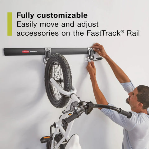 Man installing the FastTrack Garage Wall Mounted Storage Kit with four rails and eleven hooks, holding a bicycle.