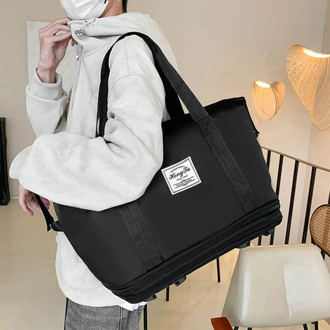 Black rolling duffle bag with top handles and shoulder strap, side view