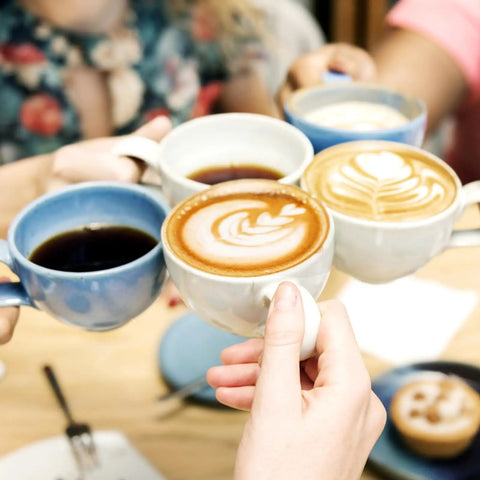 People toasting with coffee mugs, showcasing latte art and black coffee, related to Unbleached Round Disposable Coffee Filters, 600 Count, 64 Mm 2.5 Inch Size, Fits Most Drip Pots And Espresso Machines, Easy Cleanup, Absorbs Oils For Cleaner Smoother Tasting Coffee Keeps Your Cup Clean.