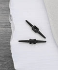 Two black Ten Pack 26mm Bicycle Cable Connectors for Brake and Shift Cables, 2mm aperture, shown on a textured surface.