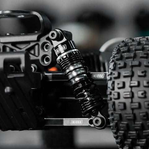 Close-up of 59mm Aluminum Oil Shocks with Adjustable Damping mounted on RC car, showing CNC machined aluminum construction and nylon rod ends.