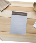 Waterproof Poly Mailer Bags 10x14 Inches White Self Seal Envelopes For Clothing on wooden surface