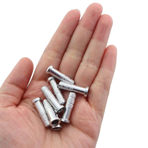 Hand holding 20 Pack Aluminum Arrow Inserts For 5.8mm Carbon Arrows Archery Target Practice with embossed texture for adhesion