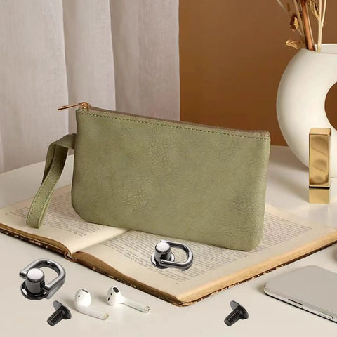 Hella Sturdy Gun Black D Ring Purse Hardware Kit Featuring Premium Zinc Alloy Ball Post Stud Screws And Slick Metal Rivets For Top Tier Leather Craft Projects on a table with a green clutch.