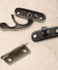 Close-up of Vintage Style Mini Swing Arm Clasp Latch Set With Dope Bronze Hinges and Antique Box Latch Hasp Lock parts on a table