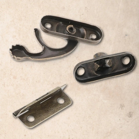 Close-up of Vintage Style Mini Swing Arm Clasp Latch Set With Dope Bronze Hinges and Antique Box Latch Hasp Lock parts on a table