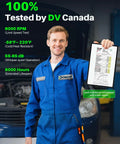 Mechanic in blue coveralls holding test report, standing in front of open vehicle hood in garage.
