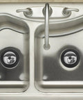 Rubber Bathtub Drain Stopper Plug with Stainless Steel Seal in a stainless steel sink; two drain openings visible.