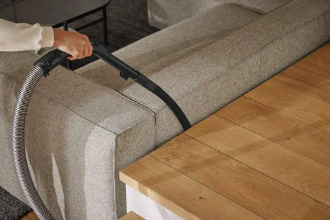 Flexible Crevice Nozzle Attachment for Canister Vacuums, 22 Inch Reach used to clean sofa corner, showing flexible center on vacuum