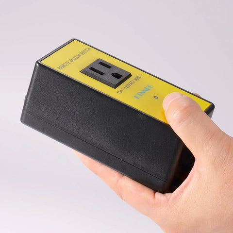 Kickstart Your Shop Setup With This Wireless Remote Automatic Vacuum Switch For 120V Dust Collectors Featuring Auto Power On Off Outlet Dual Remotes And Smart 5 To 10 Second Timer held in hand showing black body and yellow label.