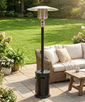 47000 BTU Outdoor Patio Heater With Round Table Design And Wheels Propane Gas Standing Heater With Double Layer 304 Stainless Steel Burner 20 Foot Radius Black Hammered Finish Perfect For Patios Decks And Backyards shown in a garden setting next to patio furniture.