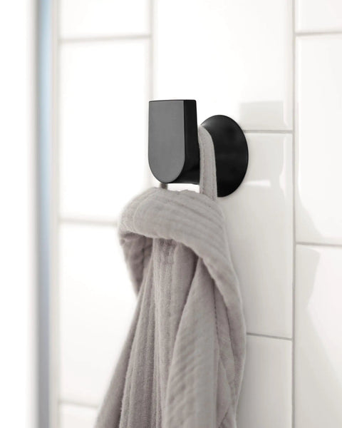 Genta LX Modern Single Robe Hook and Towel Hanger in Matte Black holding a gray robe, wall-mounted in a bathroom tile setting.
