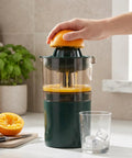 Asixxsix Portable Electric Citrus Juicer In Dark Green 400ml Cordless Handheld Fruit Press Machine With Built In Pulp Filter in use, squeezing orange.