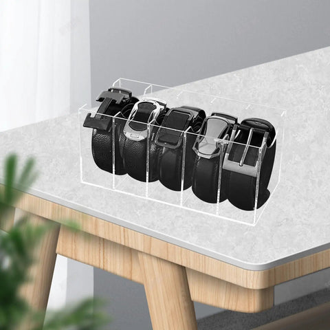 Upgrade Your Drawer Storage Vibe Today With This Sturdy Clear Acrylic Belt Organizer Designed With Five Flexible Foldable Sections To Store Ties And Belts on a table holding multiple black belts.