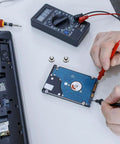 Person using multimeter on hard drive next to Ten Piece Laptop Hard Drive Screws Kit M3 Miniature Computer PC Case Screws Black Replacement Set