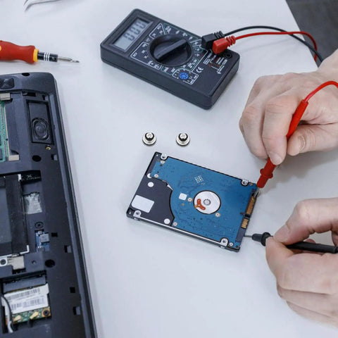Person using multimeter on hard drive next to Ten Piece Laptop Hard Drive Screws Kit M3 Miniature Computer PC Case Screws Black Replacement Set