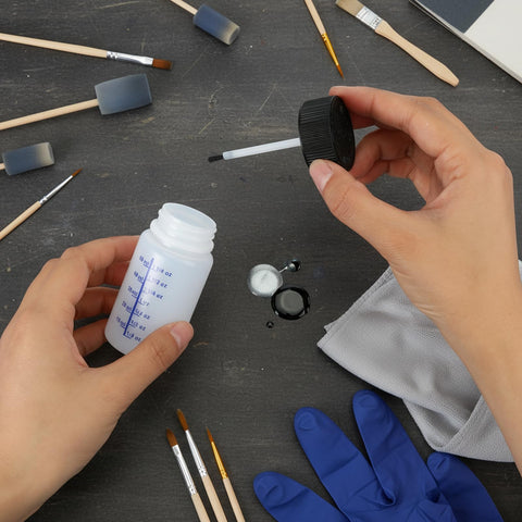 Person holding 6 Pack Empty Touch Up Paint Bottles 2 Oz Refillable Containers With Brush Applicator For Car Scratch Repair