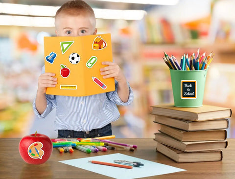 Child holding notebook with Totally Back To School Sticker Pack 47 Pcs Waterproof Decals, surrounded by school supplies.