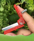 Close-up of a red Thumb Knife and Pruning Shears for Leaf Trimming and Fruit Picking in the Garden, showing precision stainless steel blades.