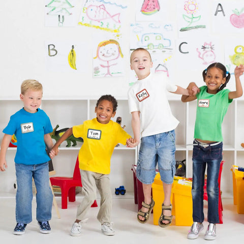 Students wearing Boho Rainbow Name Tag Stickers Pack Six Styles For Back To School And Classroom Decor 144 Pieces, jumping in a classroom.