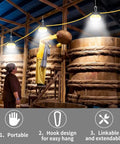 Heavy Duty 10000 Lumen LED Construction String Lights for Jobsite, 100 Ft shown over industrial barrels indoors