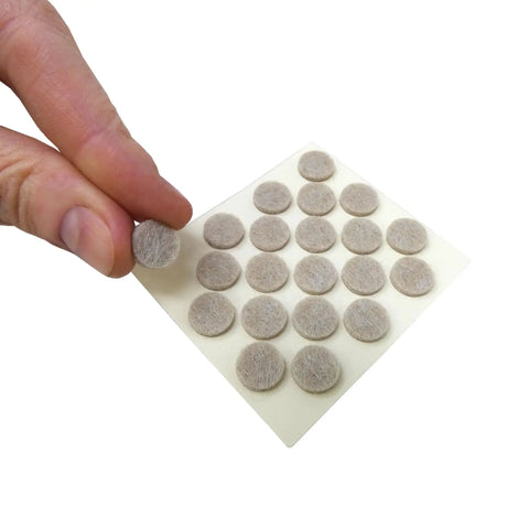 Sheet of 3/8-inch beige round mini self-stick furniture felt pads being peeled, 84-count, for hardwood, tiles, and vinyl surfaces.