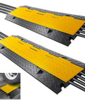 Heavy Duty Cable Protector Ramp Cover With Flip Open Top For Indoor Outdoor Use 4 Channel Cord Protection Waterproof Holds Up To 33000lbs Per Ramp 31.5 By 16.1 By 3.14 Inches 2 Pack Black And Yellow showing cables and tire crossing.
